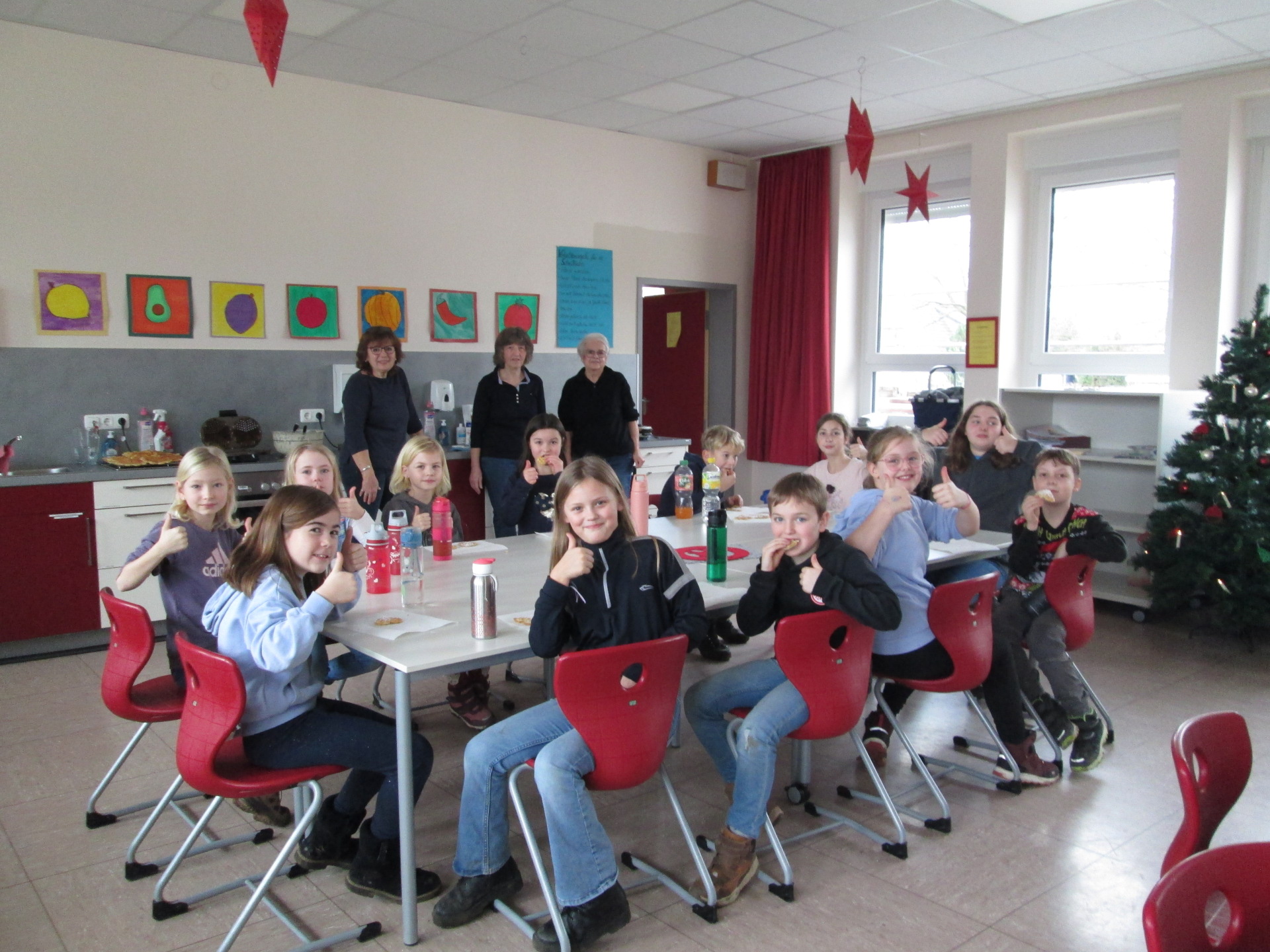 Auf dem Bild zu sehen, Kinder, die um einen Tisch sitzen; sowie die Landfrauen, die mit den Kindern Waffeln backten