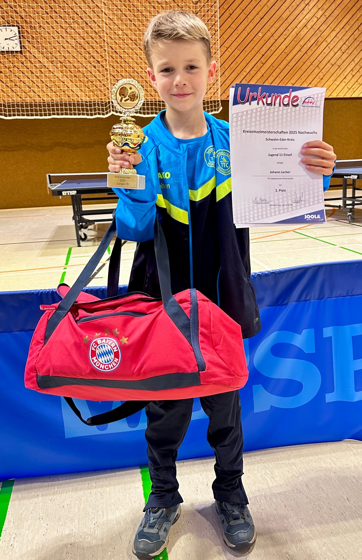 Johann Lecher mit Pokal und Urkunde in der Hand in einer Sporthalle