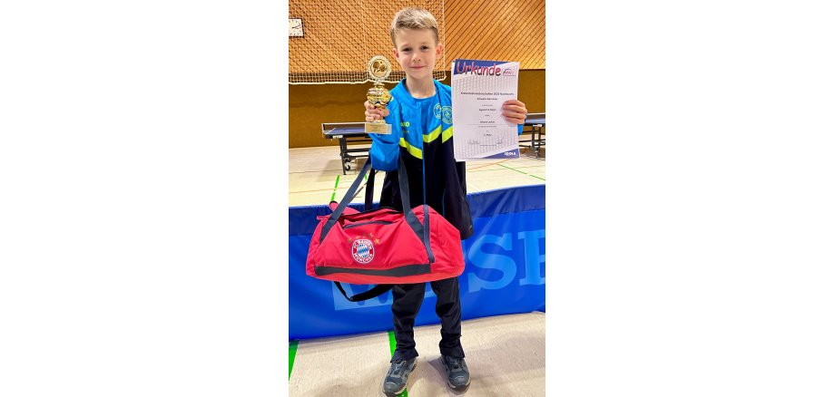 Johann Lecher mit Pokal und Urkunde in der Hand in einer Sporthalle