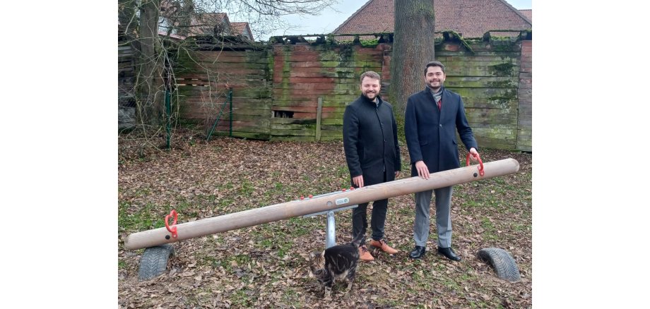 Auf dem Bild zu sehen: Bürgermeister Lukas Daum mit André Jüttner, Vertreter Leiter der EAM Netzregion Borken/Bebra neben der neuen Wippe auf dem Spielplatz in Sebbeterode