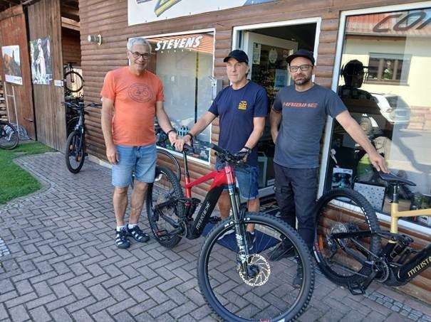 Auf dem Bild zu sehen: drei Männer mit einem Fahrrad vor dem Radgeschäft Freddys Zweiradshop